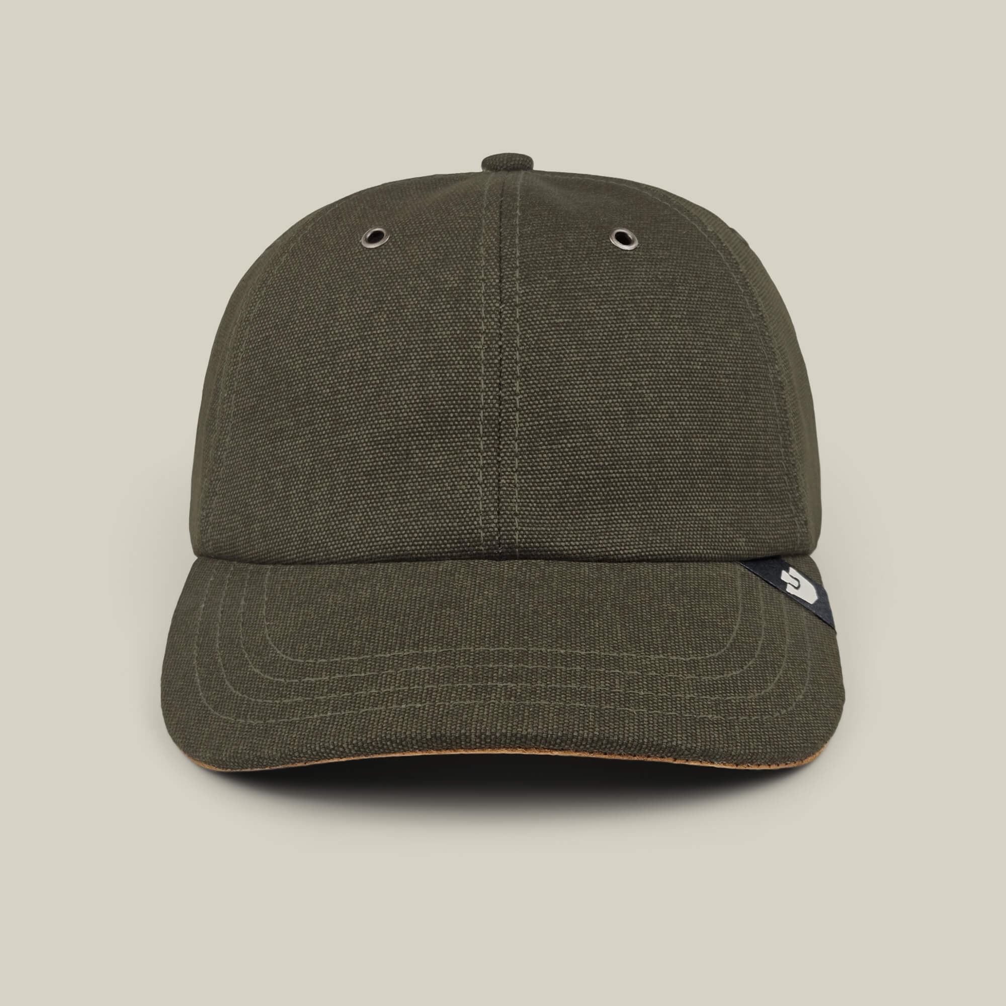 A front view of the Goorin Bros. Mineral Road baseball cap in olive green, featuring mixed materials, two metal eyelets, and a small black tag on the brim, hand cut and sewn, shown against a plain beige background.