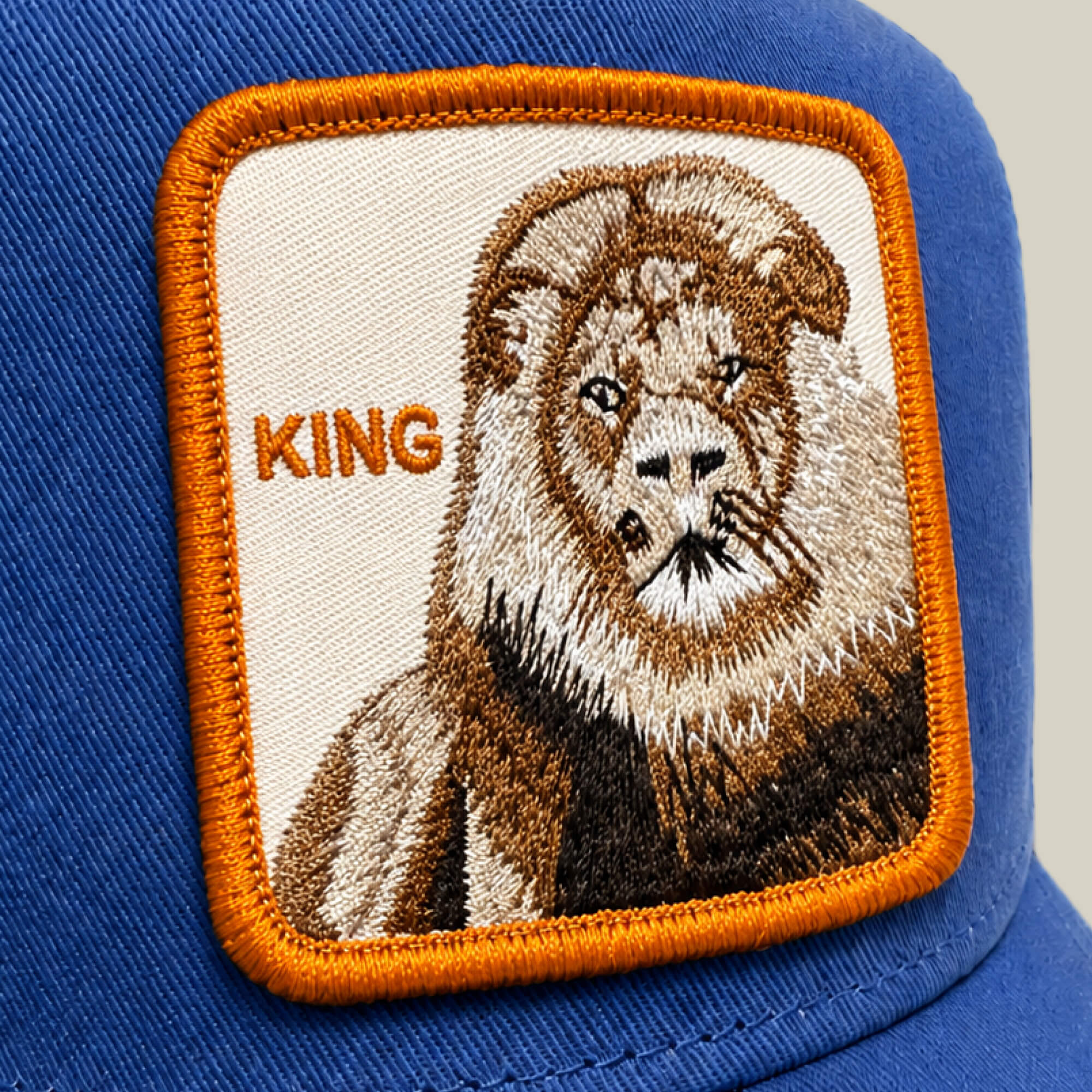 Close-up of the blue "Empire State of Mind" cap by Goorin Bros., featuring a lion embroidered patch and bold orange KING lettering. A standout accessory, now available for pre-order.