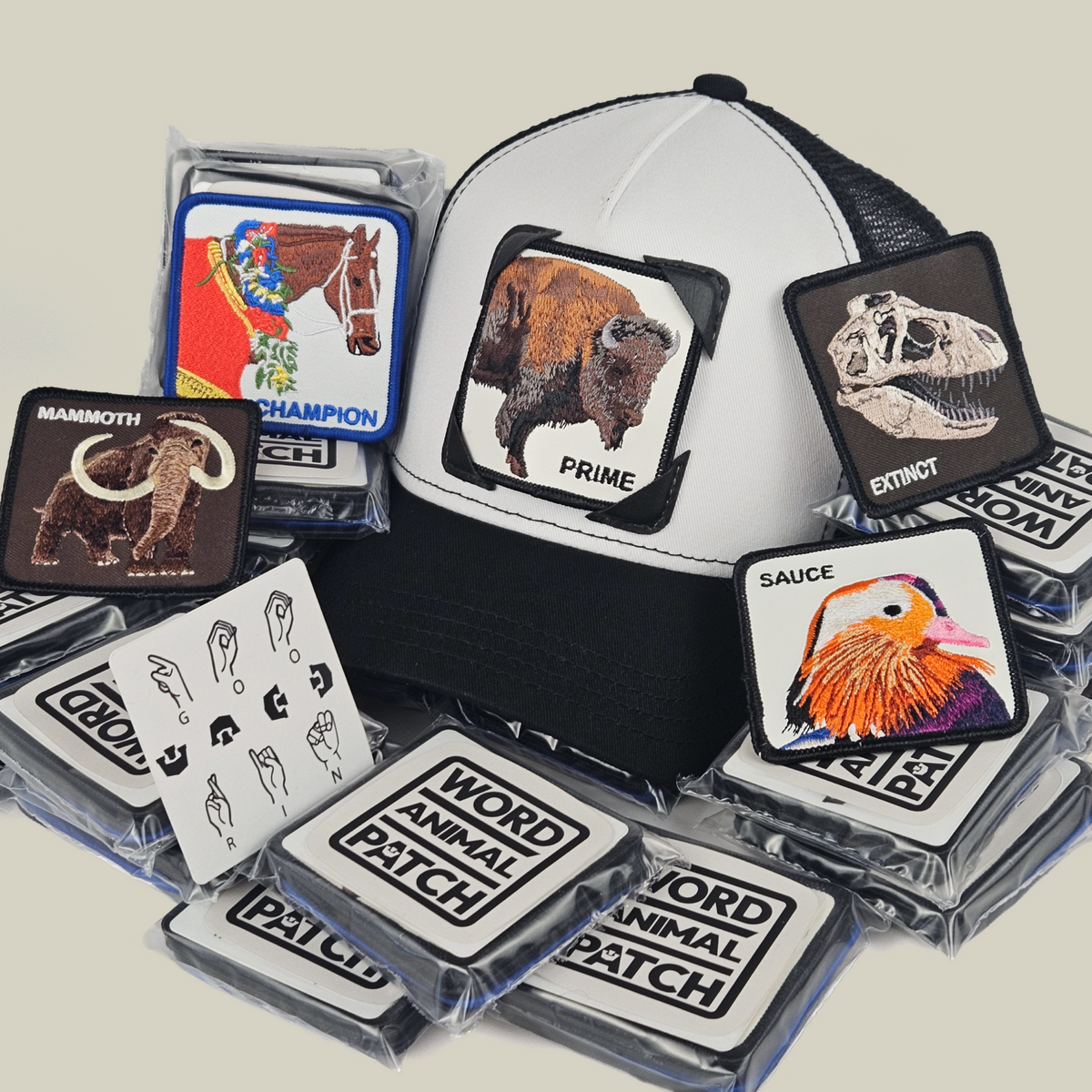 A black and white Hands Down Patch Pack with GB Patch Corner Trucker - Black and White, surrounded by animal patches—including a bison, mammoth, dinosaur skull, and duck—and an ASL card.