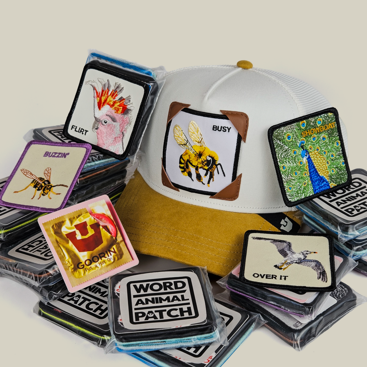 A white and tan Birds N Bees Patch Pack with GB Patch Corner Trucker - Tan hat decorated with a bee, surrounded by various stacks of assorted animal patches.