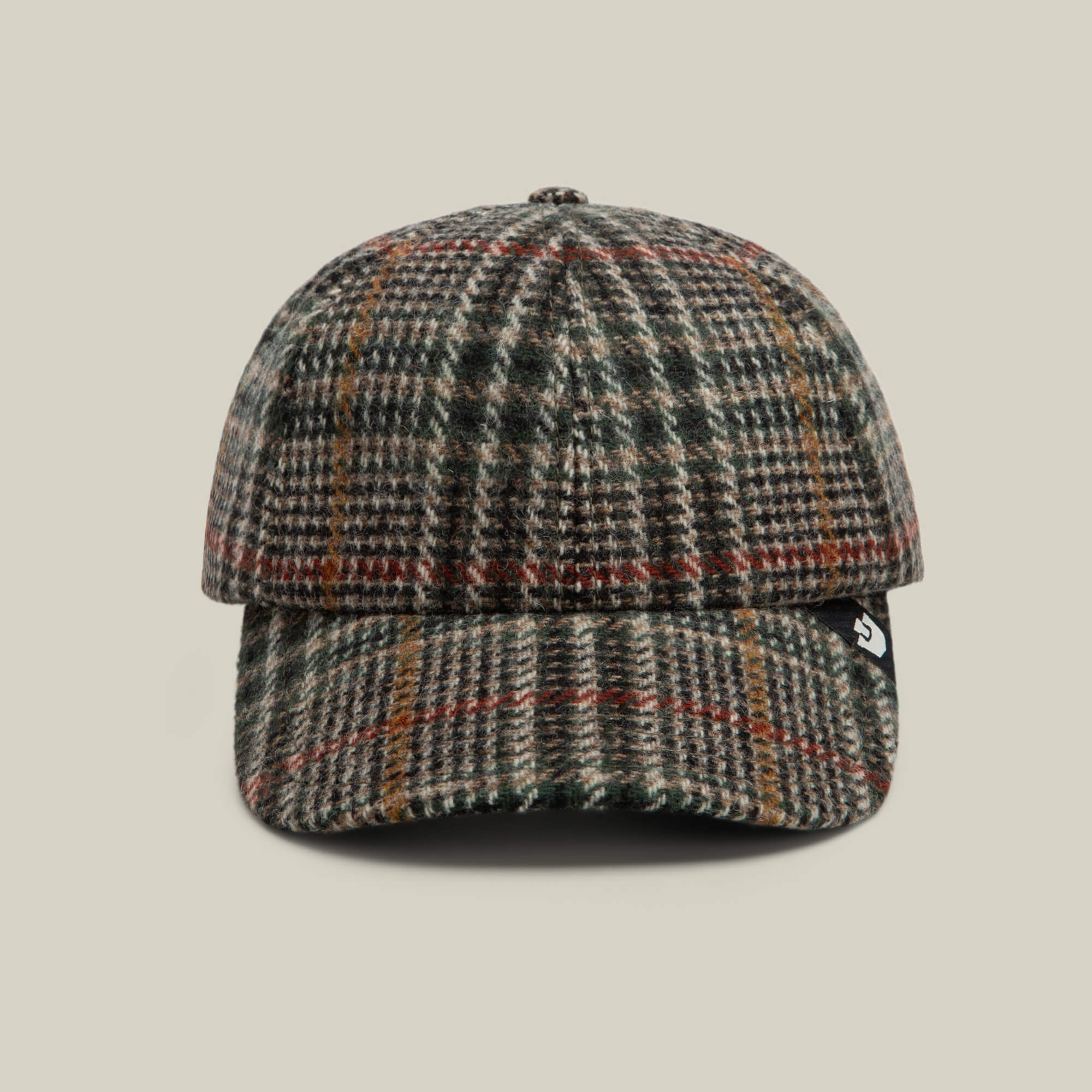 A front view of the Goorin Bros. Cozy Tailored Baseball cap in PALM, featuring a classic six-panel plaid wool design with green, brown, and red tones, finished with a small black tag on the left side.