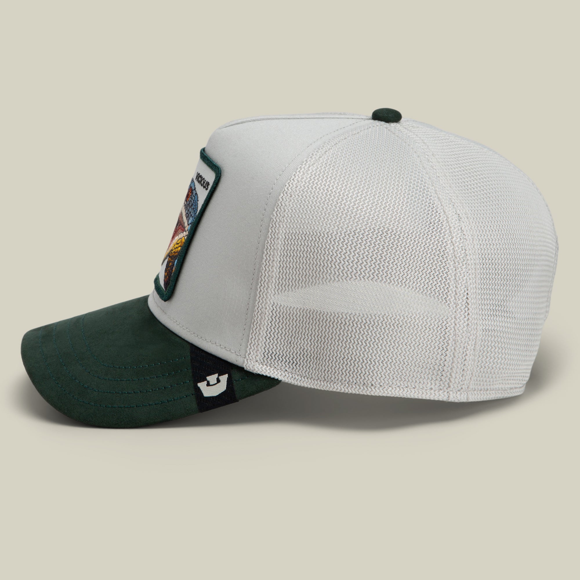 Side view of the Goorin Bros. Suede Snake trucker hat, showcasing a green suede brim, white mesh back, and a white front panel adorned with a colorful snake patch.