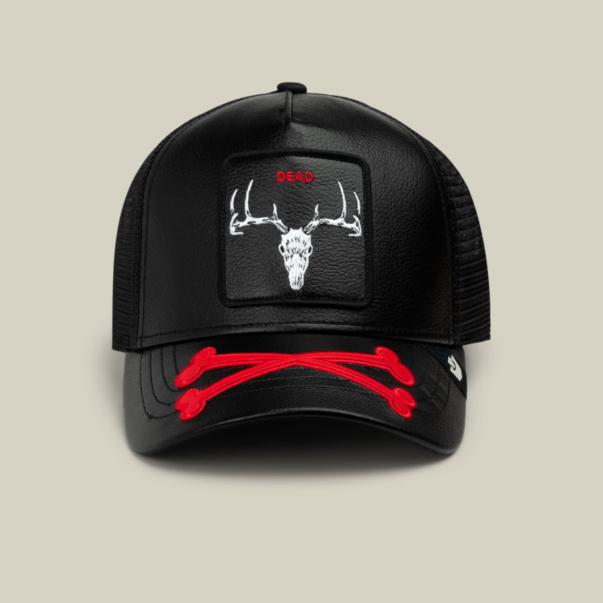 Dead Bones Trucker by Goorin Bros is a black mesh-back trucker hat featuring a white embroidered deer skull with antlers on the front panel and red text reading "DEAD" above it, with matching red stitching accents on the bill.