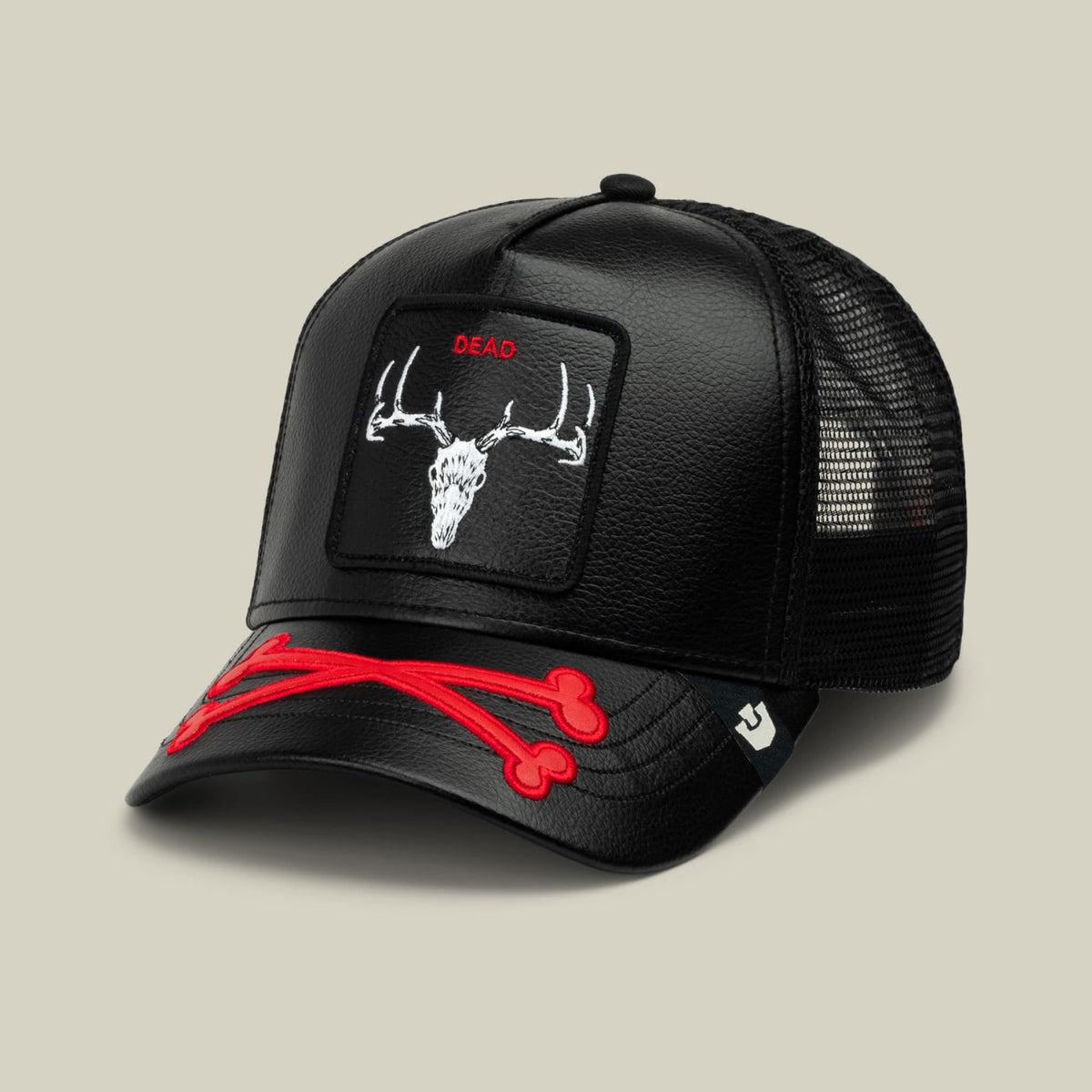The Goorin Bros. Dead Bones Trucker is a black mesh-back cap featuring a white deer skull patch with red "DEAD" text, red crossbones embroidery on the bill, and a structured leather front, shown against a neutral background.