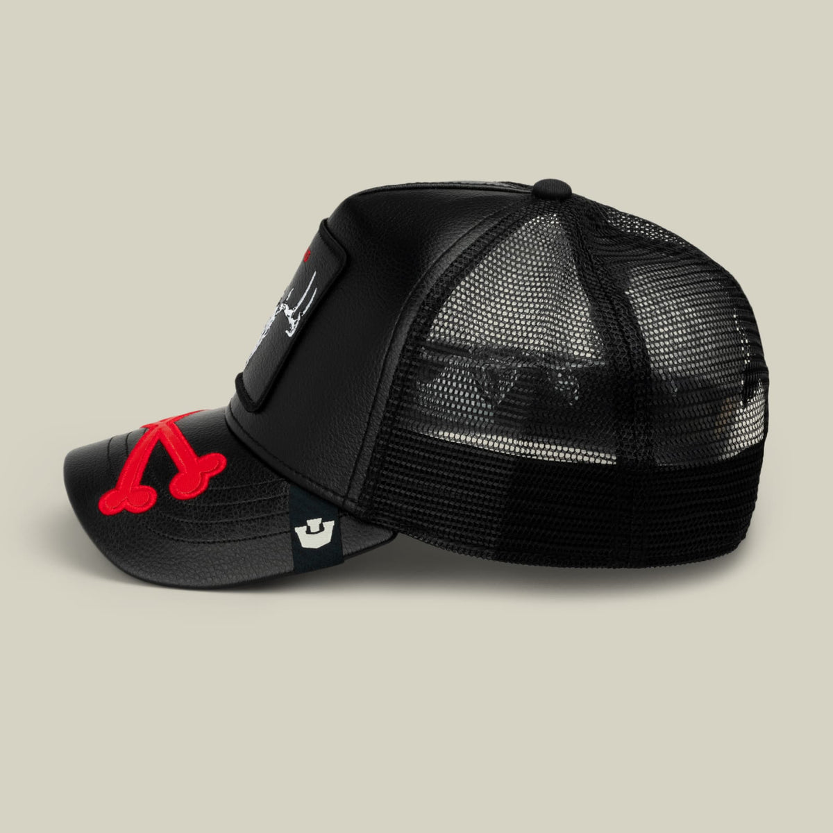 The Dead Bones Trucker by Goorin Bros is a black mesh trucker hat with red embroidered skull design on the front, featuring a snapback closure, shown in a studio product shot against a neutral background.