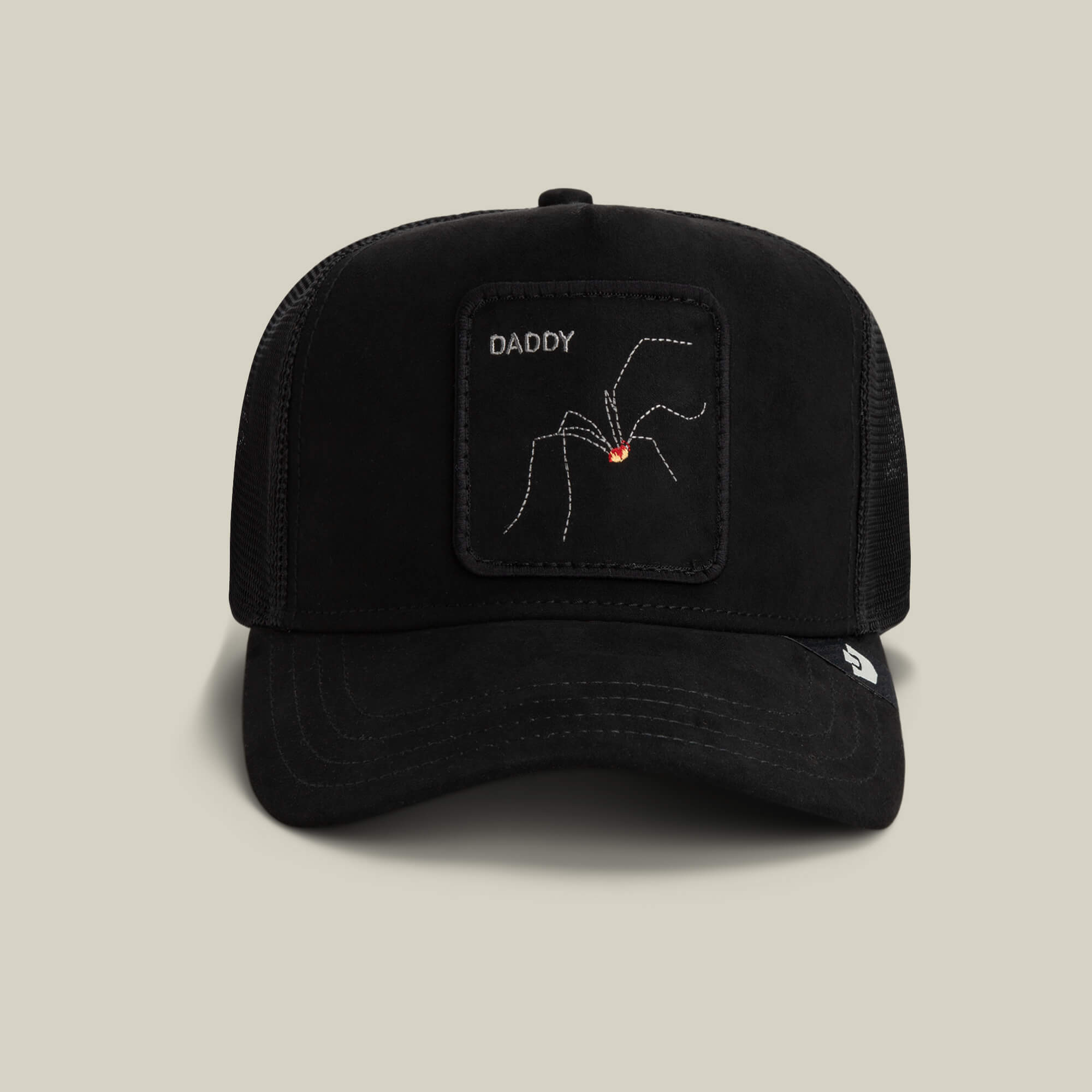 The Goorin Bros. Bold Suede Spider is a void black daddy trucker hat with a patch of an arachnid labeled DADDY and a small red mark, shown against a plain beige background.