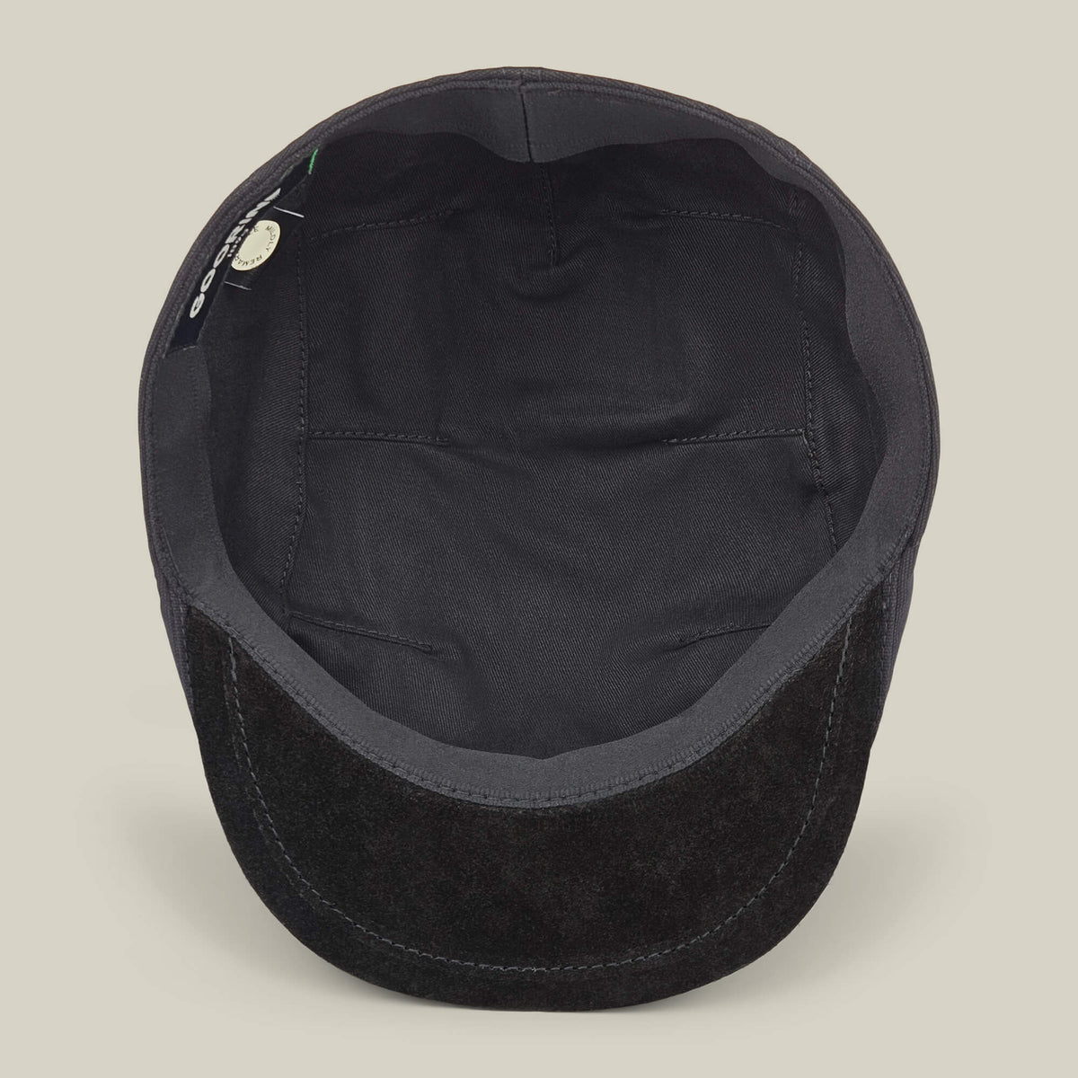 The Goorin Bros. Heatherwood is a black cotton suede flatcap, shown from above to highlight the inside lining and a small tag near the edge, emphasizing its quality craftsmanship as it is handmade in the USA.