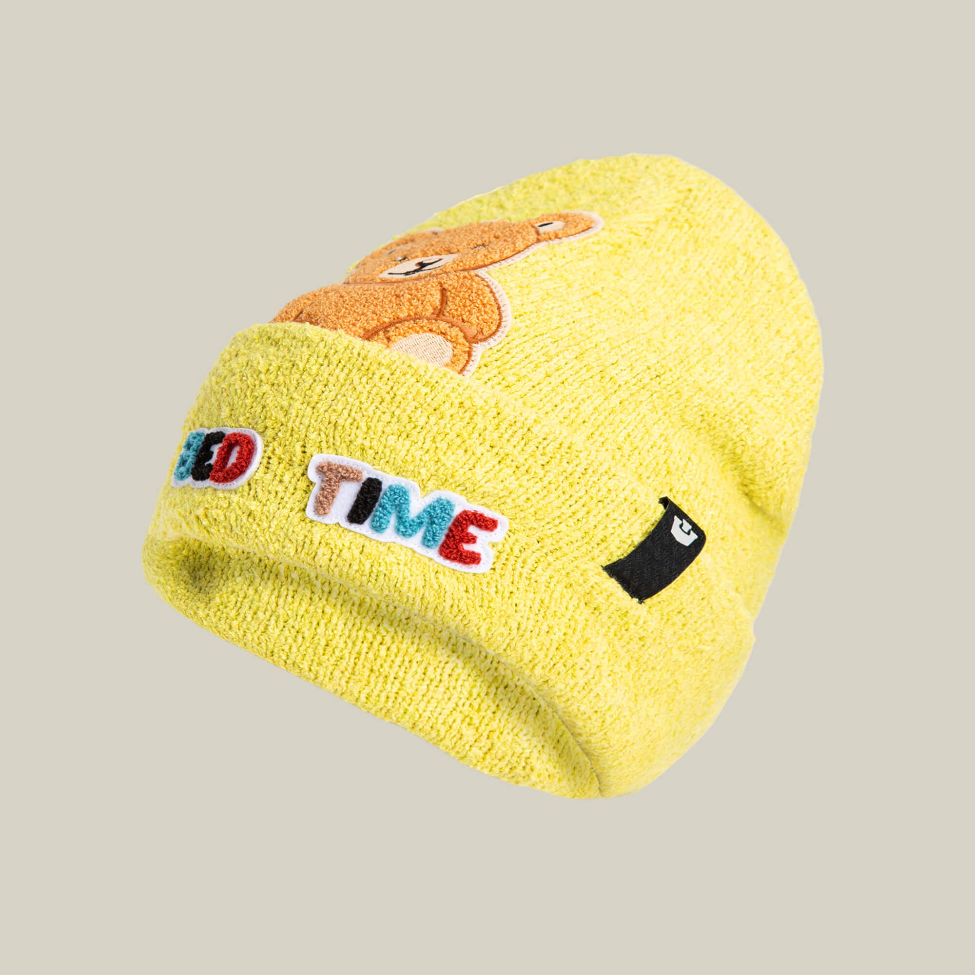 A yellow soft knit “Nap World” beanie by Goorin Bros. featuring an embroidered bear, colorful TIME text, and a black and white patch on the cuff—ideal for fans of playful sleepy bear styles.