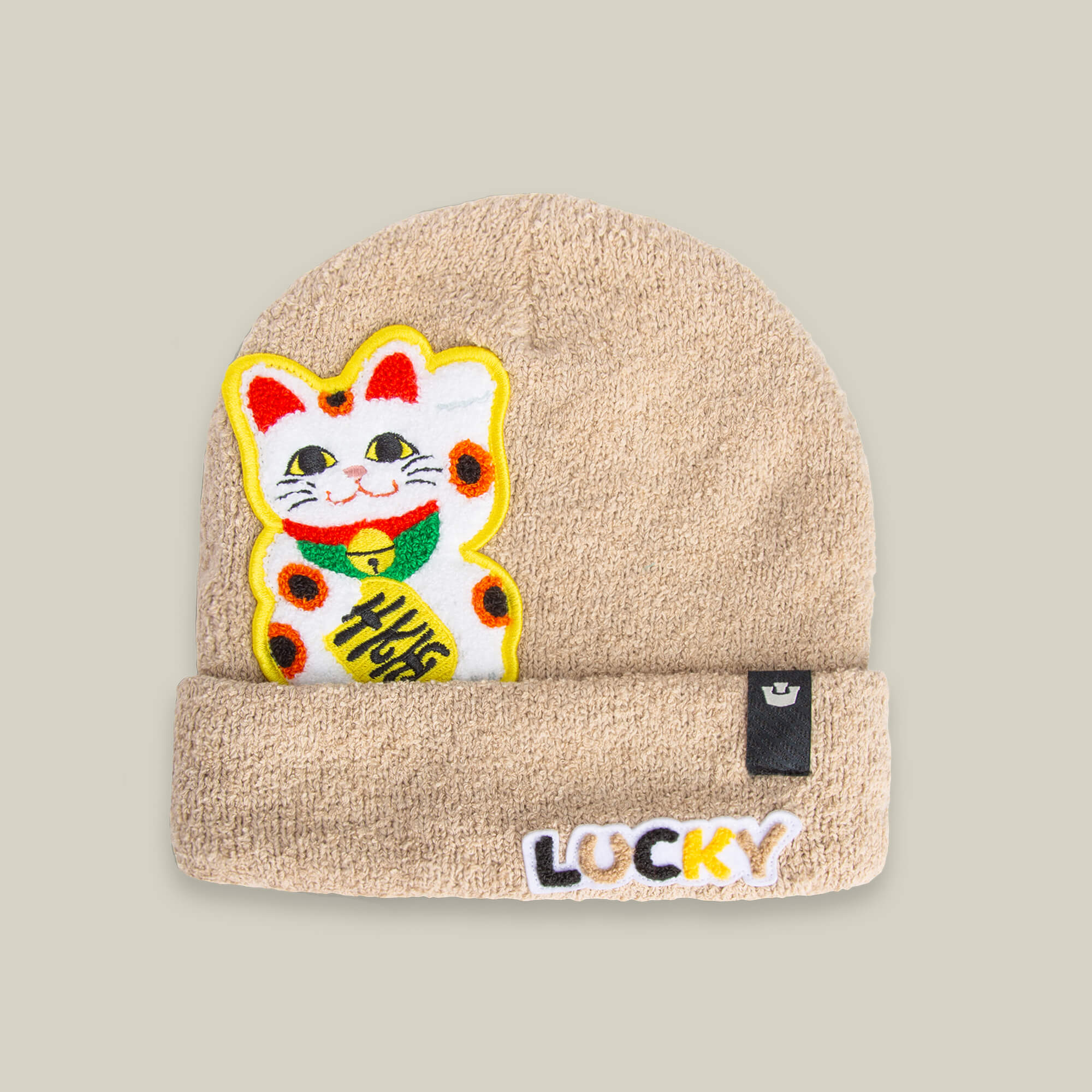 The Good Fortune beanie by Goorin Bros. is a cozy beige knit hat with a colorful embroidered lucky cat patch and "LUCKY" stitched on the cuff.