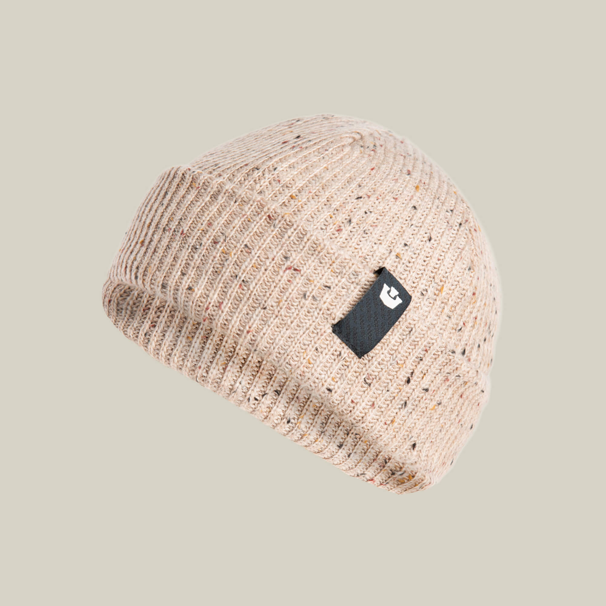 The Goorin Bros. No Comply beanie is a warm beige knit with a folded brim and a black patch featuring a white logo, set against a plain light background—ideal for cozy, stylish comfort.