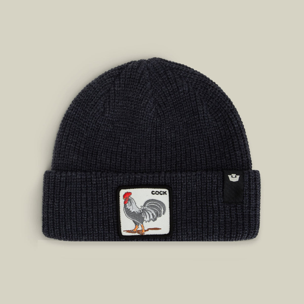 The Rooster Beanie by Goorin Bros is a black ribbed knit beanie featuring an embroidered rooster patch with red and orange details on the front, displayed against a neutral background.