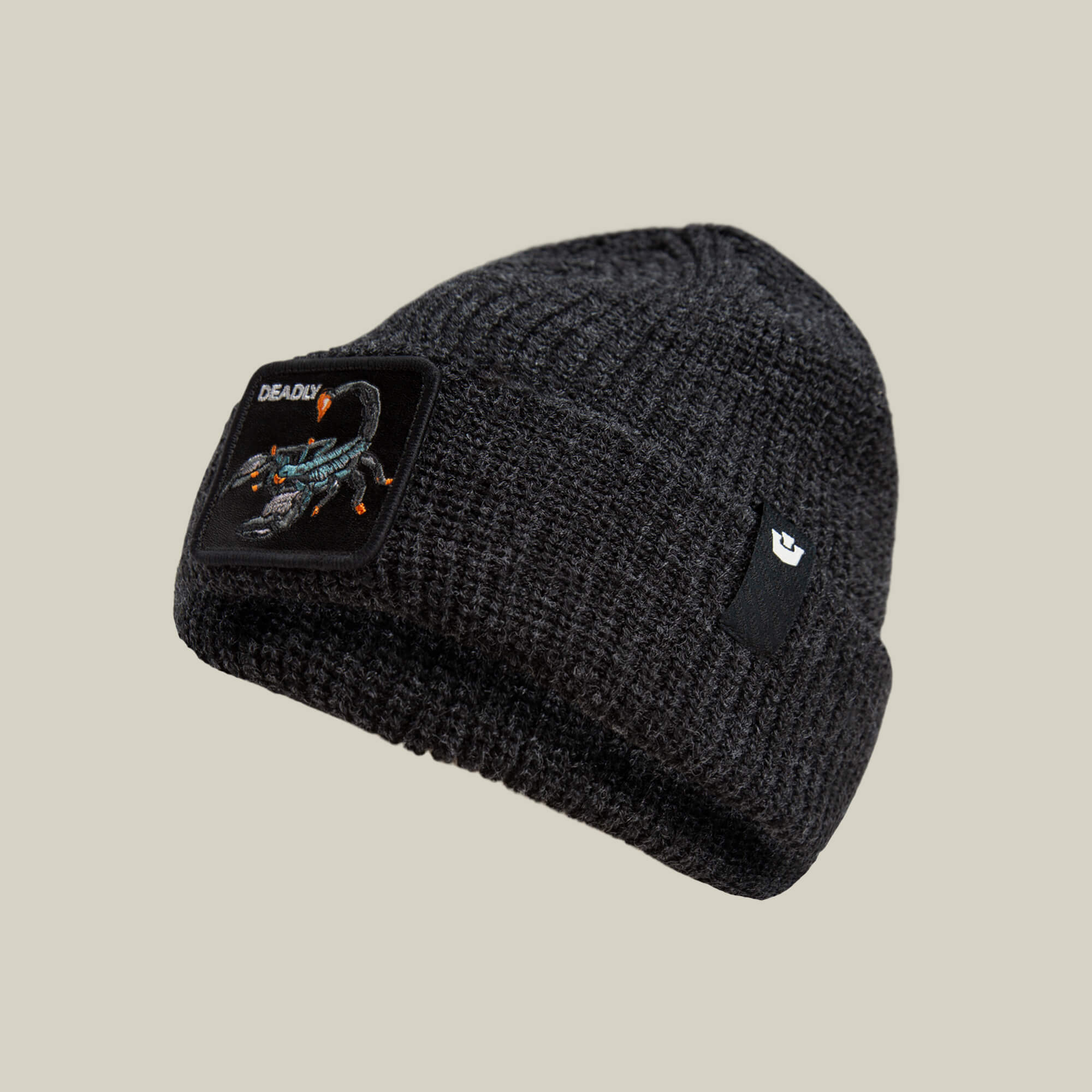The Deadly Beanie by Goorin Bros. is a dark gray winter knit hat featuring a scorpion patch and "DEADLY" embroidered on the front, displayed on a plain background.