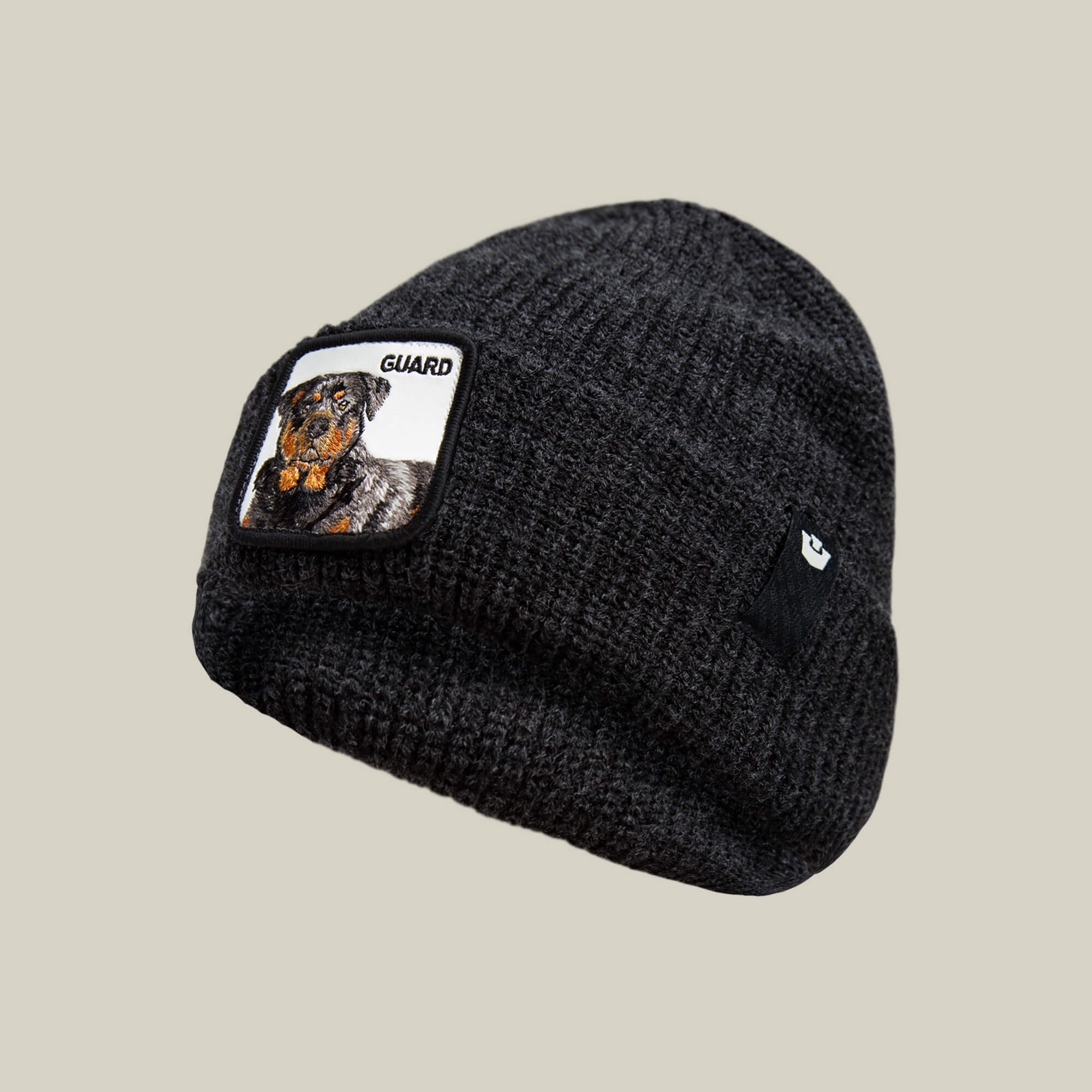 The Guard Beanie by Goorin Bros. is a black knit winter hat with a Rottweiler patch labeled "GUARD" on the front and a subtle black logo tag on the side—ideal for making a statement in cold weather.