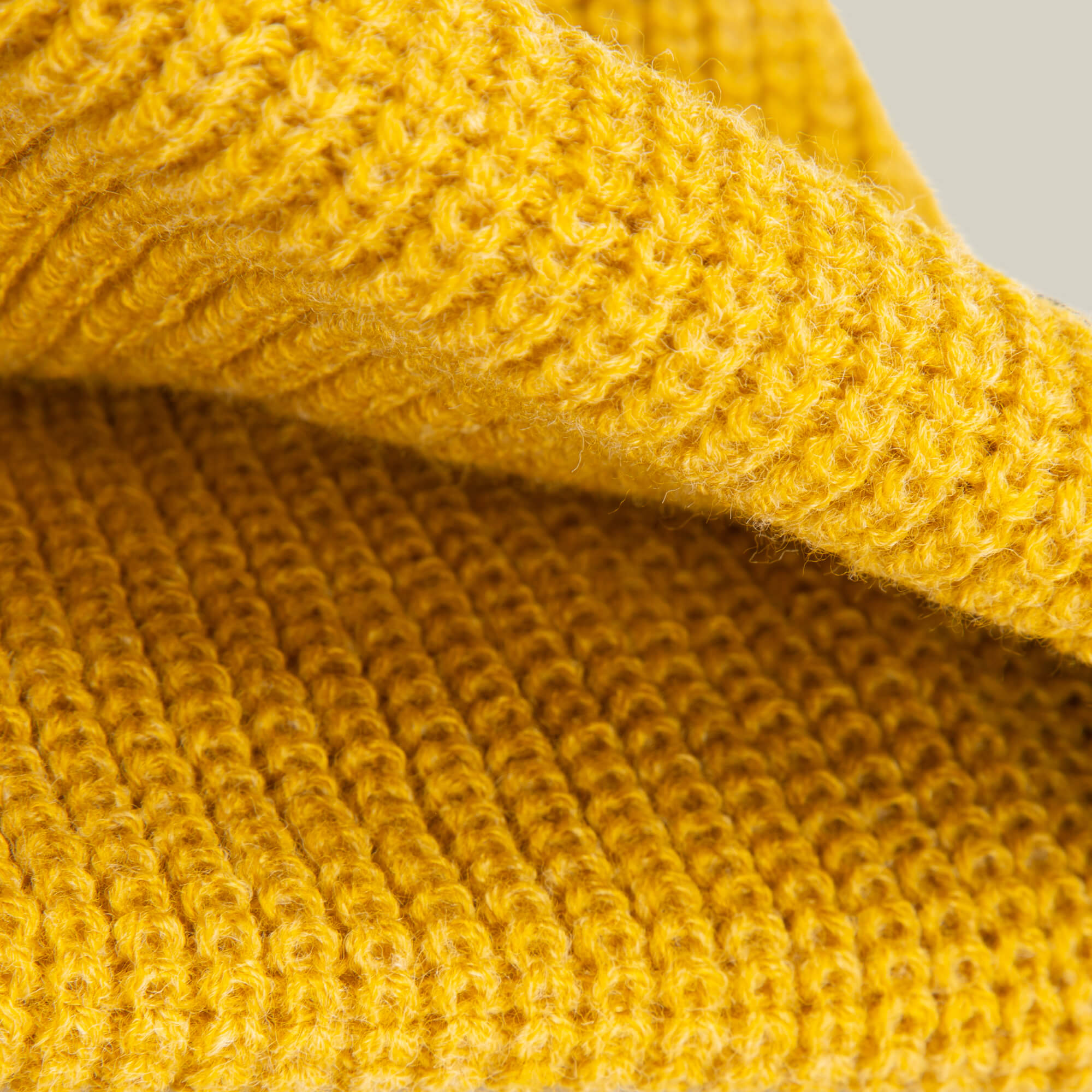 Close-up of folded yellow knitted fabric from the Goorin Bros. Air to Fakie, featuring an all-season ribbed pattern and soft fibers—ideal for a lightweight poly knit Watchman beanie.