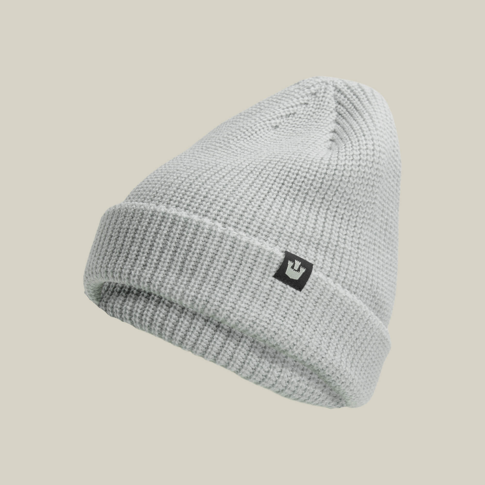 The Goorin Bros. Air to Fakie beanie in light gray features lightweight poly knit, a folded brim, and a small black rectangular logo patch on the front, making it perfect for all-season wear. Displayed against a plain beige background.