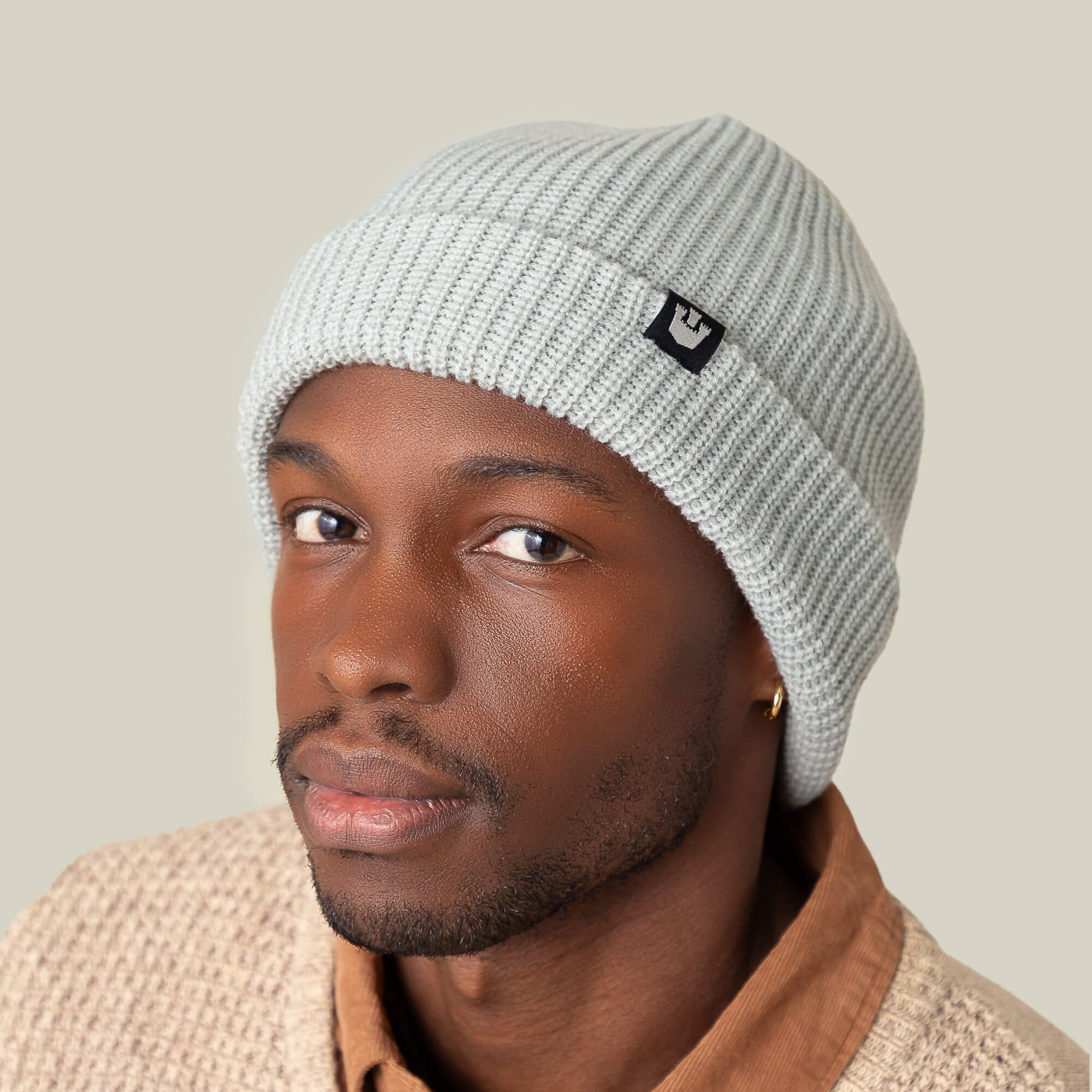 A person wearing a light gray Goorin Bros. Air to Fakie all-season beanie and a beige sweater looks at the camera against a neutral background.