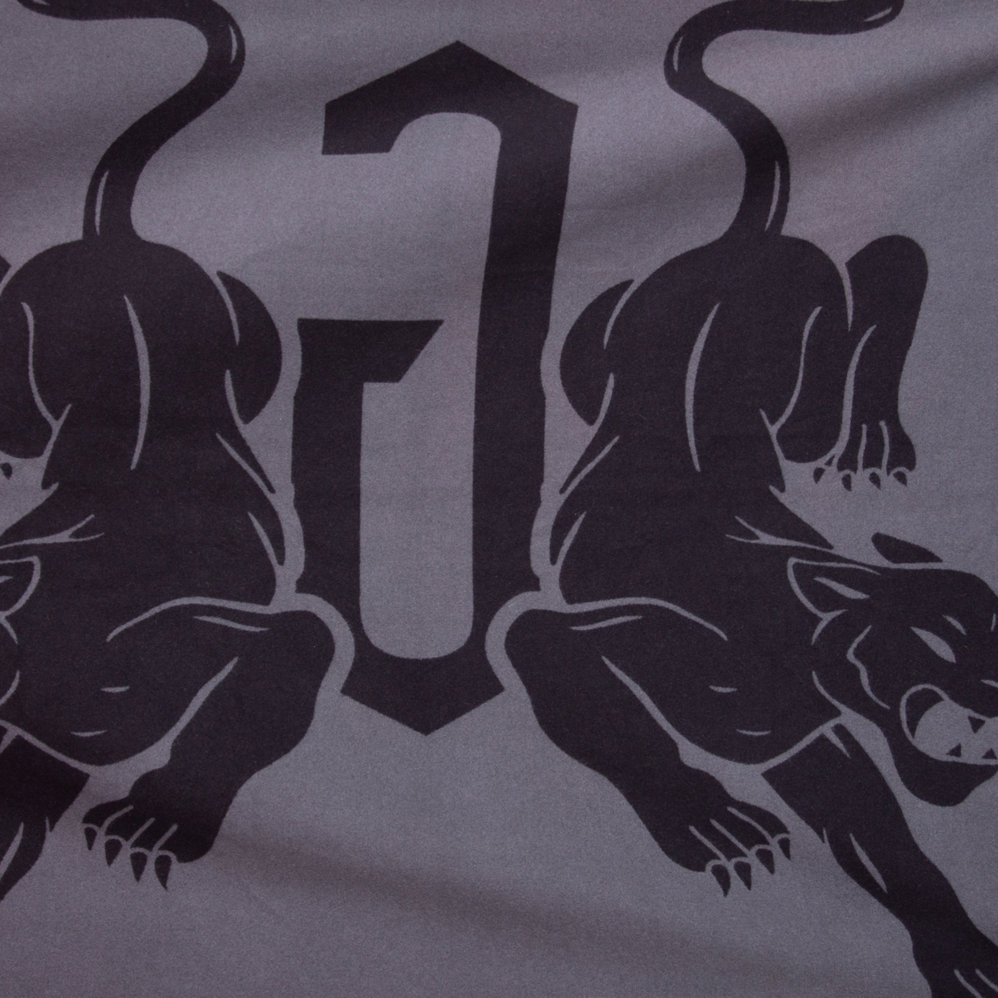 A graphic design of two black panthers facing away from a large, stylized letter J on gray decorates the Panther Crest Blanket by Goorin Bros.—the perfect luxury throw.