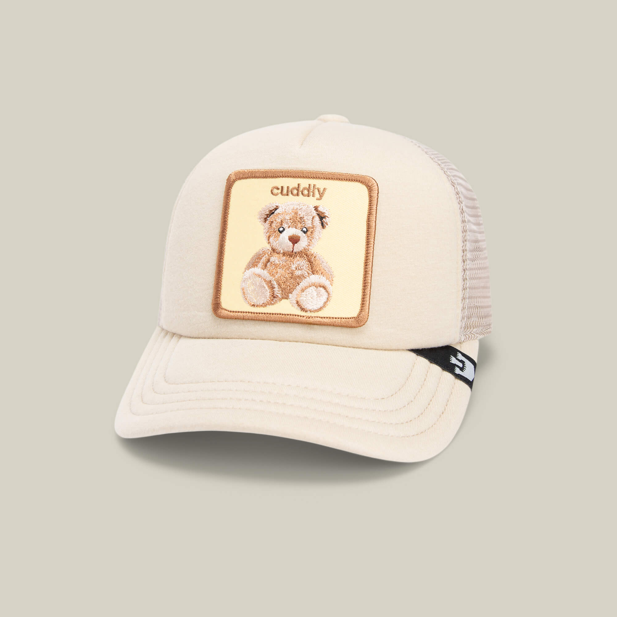 The Cuddle Time cap by Goorin Bros. is a beige teddy bear hat with a mesh back and a "cuddly" embroidered patch, making it the perfect cozy accessory for playful days.