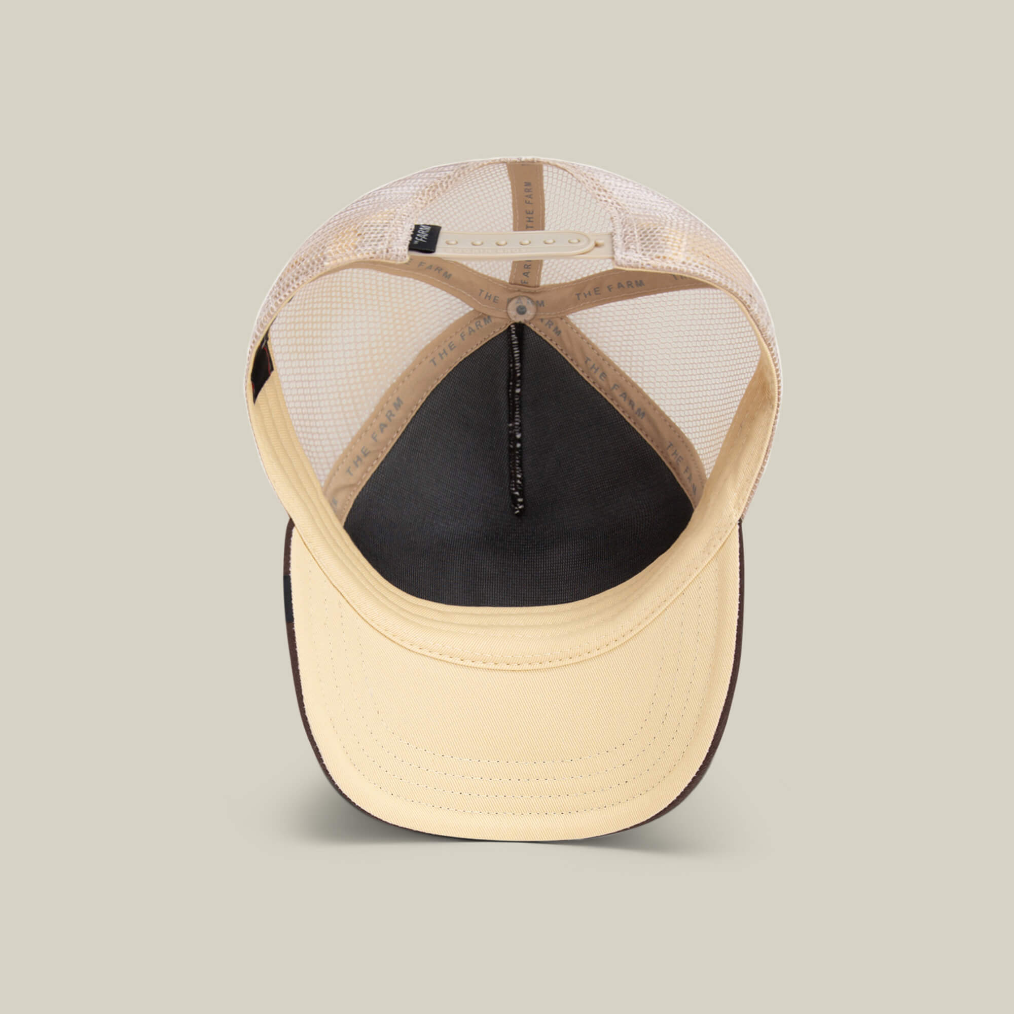 The Chaser by Goorin Bros. is a beige and black trucker hat with a breathable mesh back, adjustable strap, inside stitching, and an embroidered coyote patch.