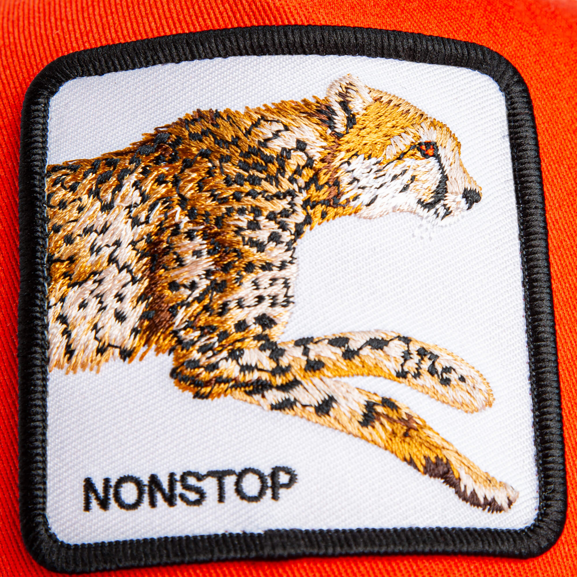 The Nonstop Cheetah Mini by Goorin Bros. features an orange crown and a sewn-on patch with an embroidered cheetah and the word "NONSTOP" for kids.