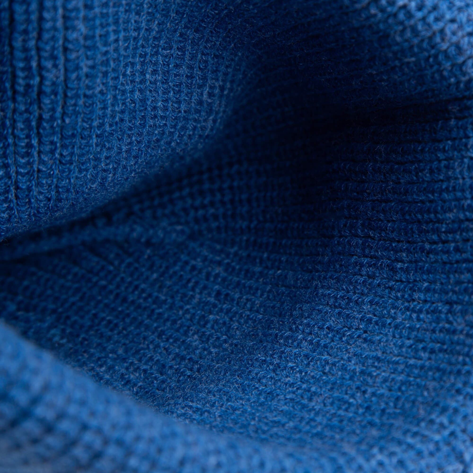 Close-up of blue knitted fabric reveals the detailed texture and weave pattern on The Penguin Beanie Mini by Goorin Bros.—a cozy snow day hat for kids.