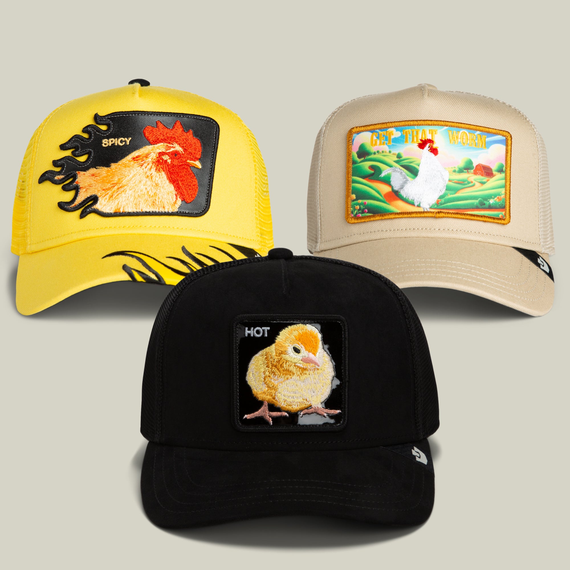 Discover the Colonel’s Choice Bundle from Goorin Bros.: a trio of distinctive trucker hats adorned with embroidered chicken designs. This exclusive set includes a yellow cap featuring a bold rooster, a tan hat showcasing a scenic landscape with a white chicken, and a black “Hot Chick” cap with charming chick embroidery. Each hat is presented against a plain backdrop.