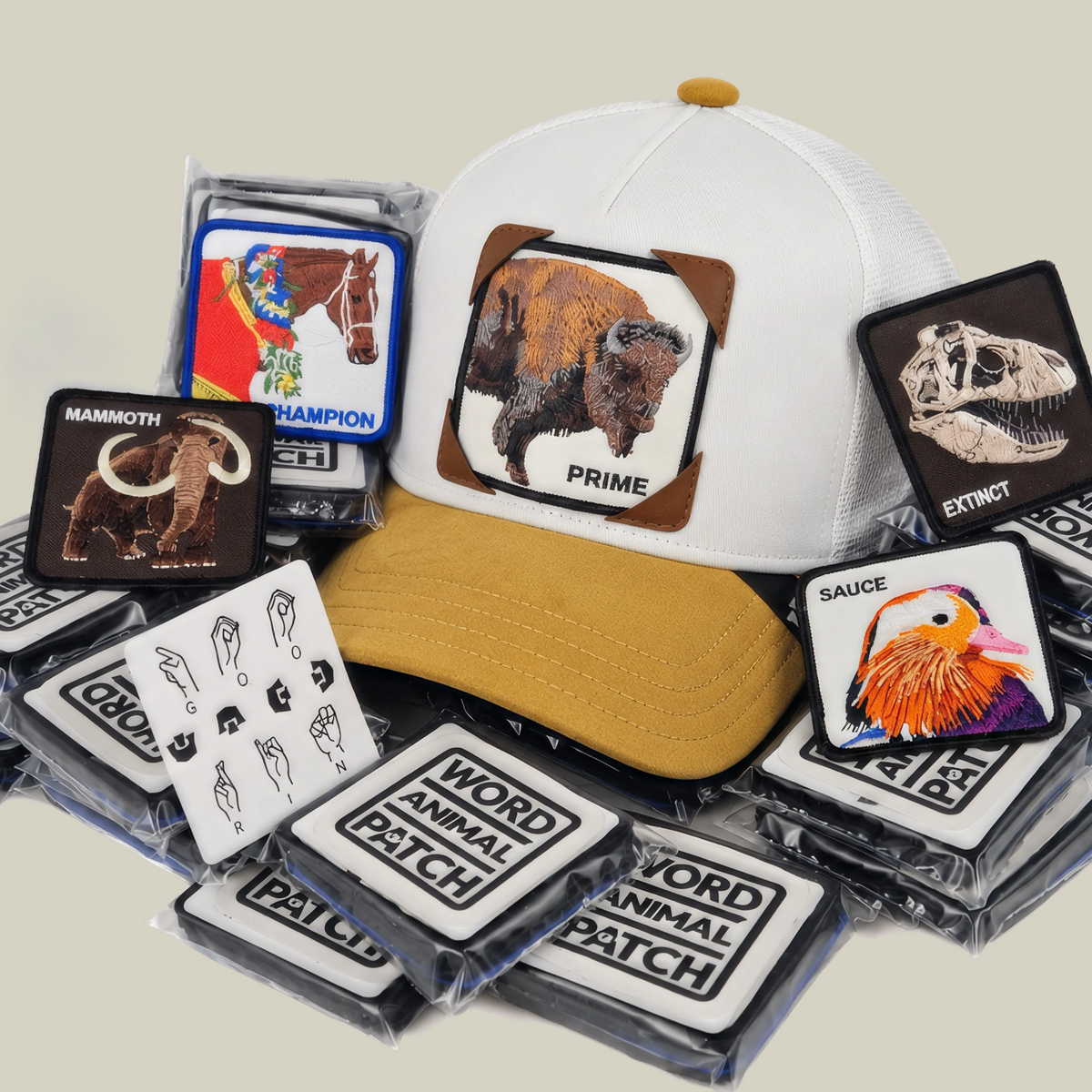 A white and tan Hands Down Patch Pack with GB Patch Corner Trucker - Tan hat sits alongside a collection of limited edition animal patches in plastic packaging.