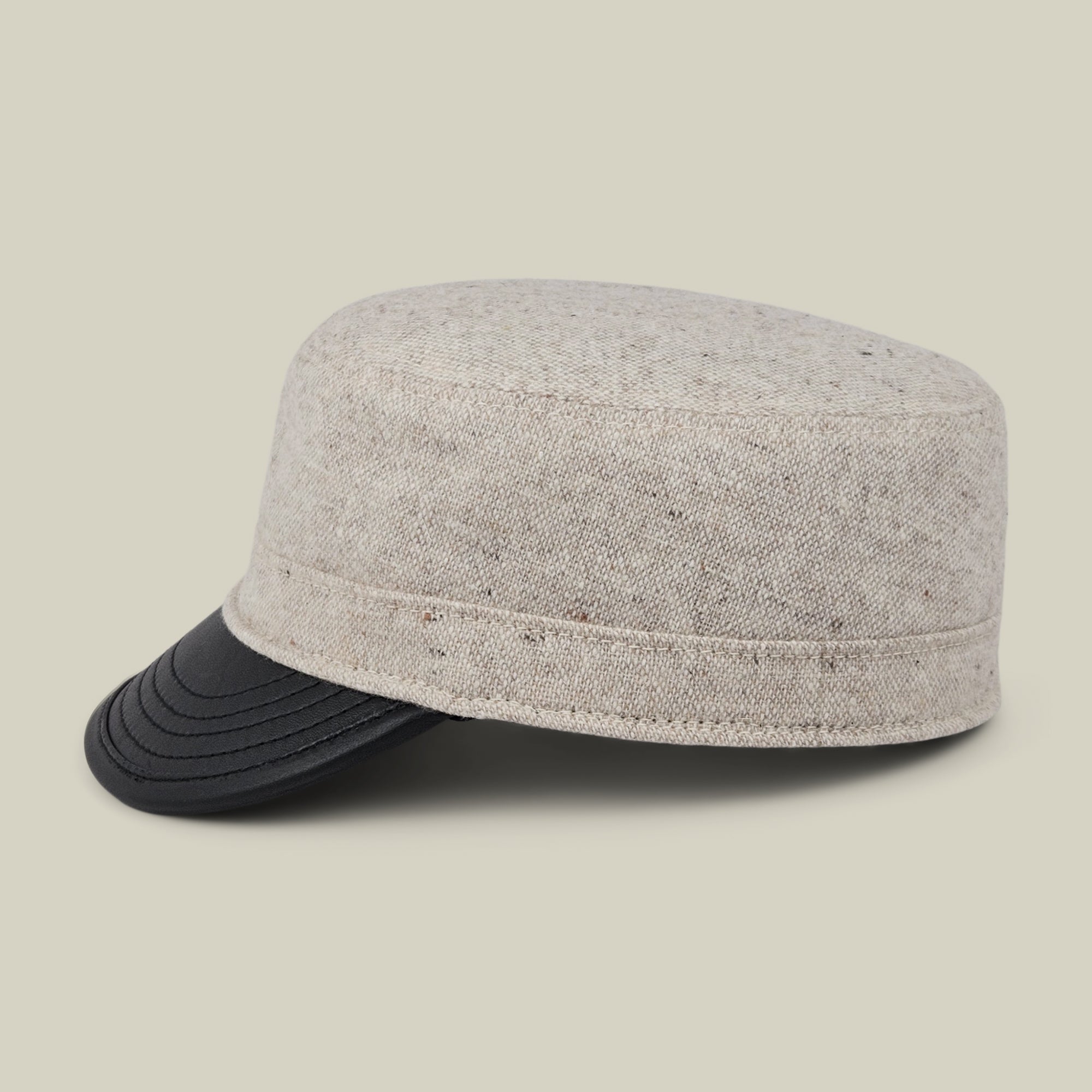 The Goorin Bros. South Boulder cap, a heritage-inspired beige tweed style with a black curved visor, is displayed against a plain light background. Expertly hand cut and sewn in the USA from quality wool and leather, this cadet cap showcases exceptional craftsmanship and timeless design.