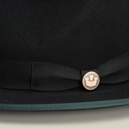 Close-up of the Goorin Bros. “River Gray,” an American-made black merino wool fedora, featuring a ribbon band and a round metallic emblem with a castle design.