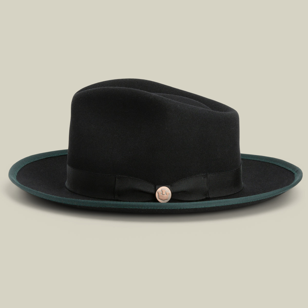 River Gray by Goorin Bros.—a black merino wool fedora featuring a wide brim, black ribbon band, and a round metallic pin on the front—is displayed on a neutral background. This American-made hat combines classic style with premium craftsmanship.