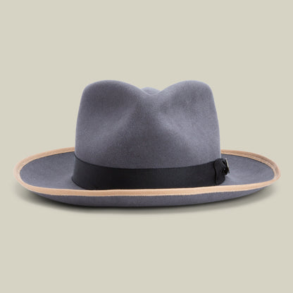 The River Gray fedora by Goorin Bros. features soft gray merino wool, a black ribbon band, and a light brown edge on the wide brim, set against a plain beige background. Crafted in America, this hat seamlessly blends timeless style with exceptional quality.