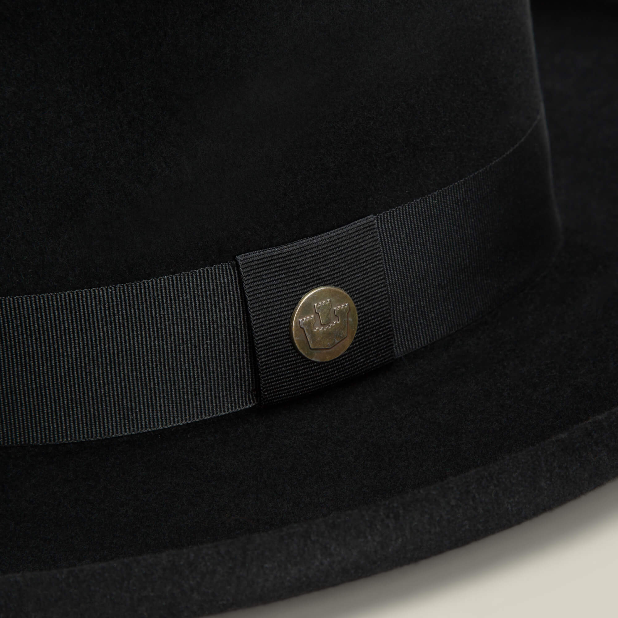 Close-up of the Goorin Bros. Colonel Pierce hat in black felt, featuring a grosgrain ribbon, small round metal pin, and a classic teardrop crown.