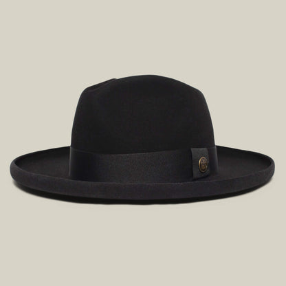 The Goorin Bros. Colonel Pierce is a black wide-brimmed fedora with a teardrop crown, black ribbon, and round metal emblem on the side, showcased against a plain beige background.