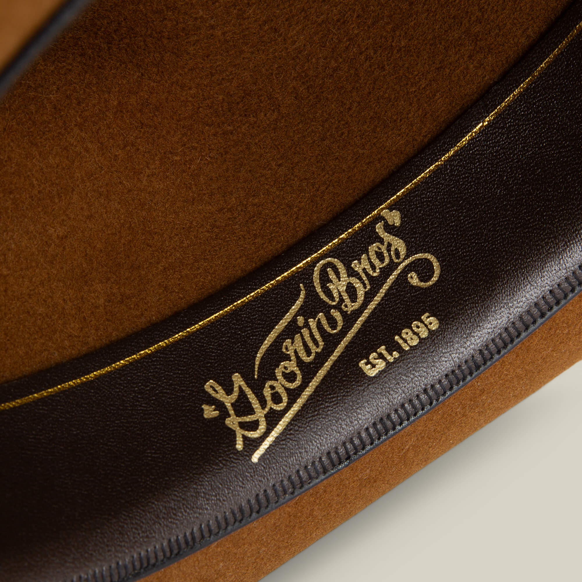 Close-up of the Night Hawk fedora's interior by Goorin Bros., featuring a black band with the gold logo and EST. 1895—an all-season hat crafted for timeless style.