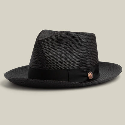 The Goorin Bros. John Sr. is a black woven toquilla fedora with a wide brim, black ribbon band, and small round metal emblem. Designed for sun protection (UPF 50), it's shown on a neutral background.