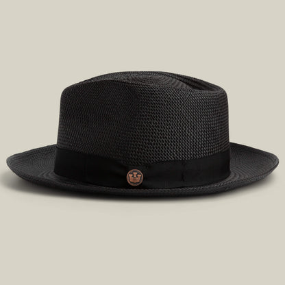 The John Sr. by Goorin Bros. is a black toquilla teardrop fedora with a black band, round metallic side emblem, and 50 UPF sun protection, shown on a plain beige background.
