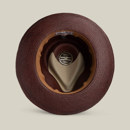 A top-down view of the Goorin Bros. John Sr. toquilla teardrop fedora highlights its brown woven finish, inner leather sweatband, beige crown support, and inside label—offering both style and UPF 50 sun protection.