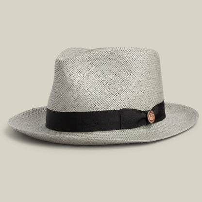 The Goorin Bros. John Sr. is a light toquilla teardrop fedora with a wide brim, black ribbon band, circular side emblem, and 50 UPF sun protection, shown against a plain background.