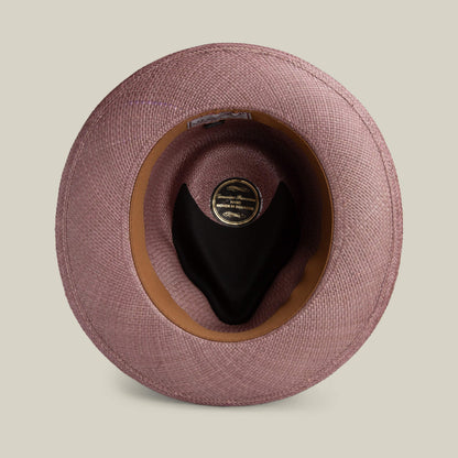 Top view of the John Sr. teardrop fedora by Goorin Bros.—pink toquilla straw, black interior lining, brown inner band—displayed on a light beige background. Stylish and provides UPF 50 sun protection.
