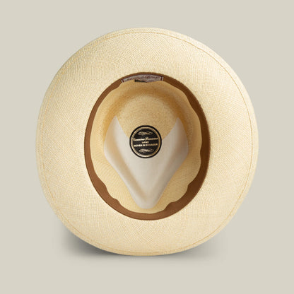 A top-down view of the Goorin Bros. John Sr. beige toquilla fedora, featuring a brown inner band, inside label, and built-in UPF 50 sun protection.