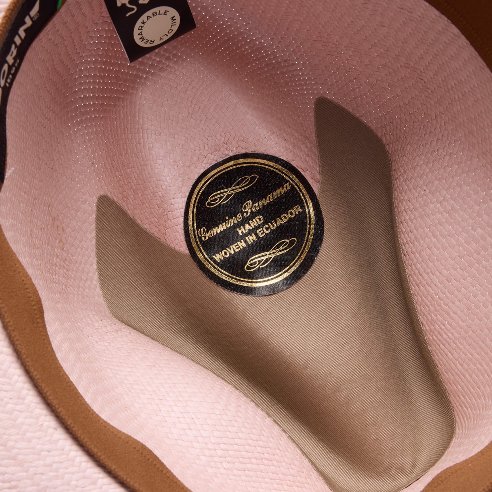 Close-up of the inside of the Hartman hat by Goorin Bros., showing a label and beige-brown lining, highlighting its 100% toquilla straw construction and hand-woven craftsmanship in Ecuador.