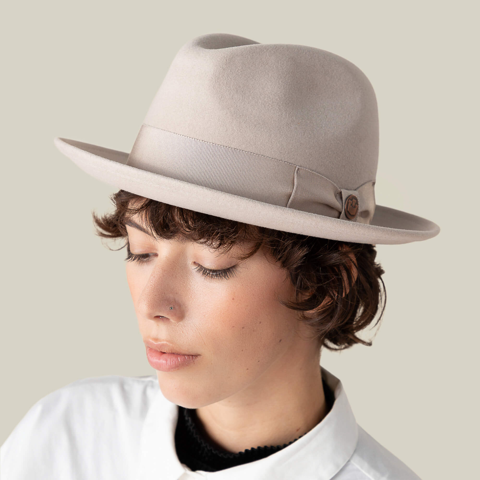 A person with short brown hair wears the Goorin Bros. Dean the Butcher, an American-made fedora featuring a German wicking sweatband, paired with a white collared shirt and looking downward against a neutral background.
