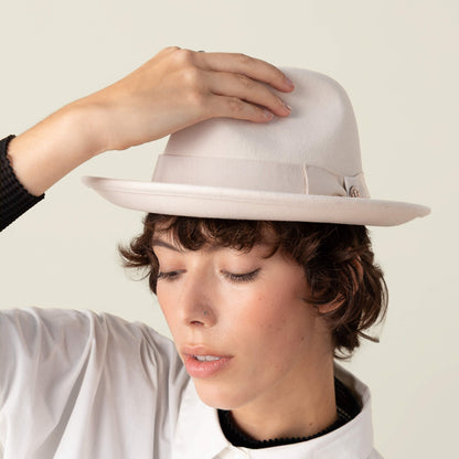 A person wearing the Goorin Bros. "Dean the Butcher" fedora with a grosgrain hatband and white shirt, tilting their head down and touching the brim.