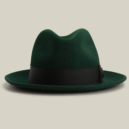 Dean the Butcher by Goorin Bros.: an American-made dark green fedora with a black ribbon band, shown on a plain beige background.