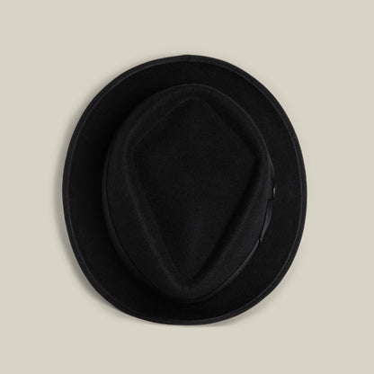 The Goorin Bros. Slick Carter is a black wool short-brim fedora, shown from above on a beige background—an effortless style statement.