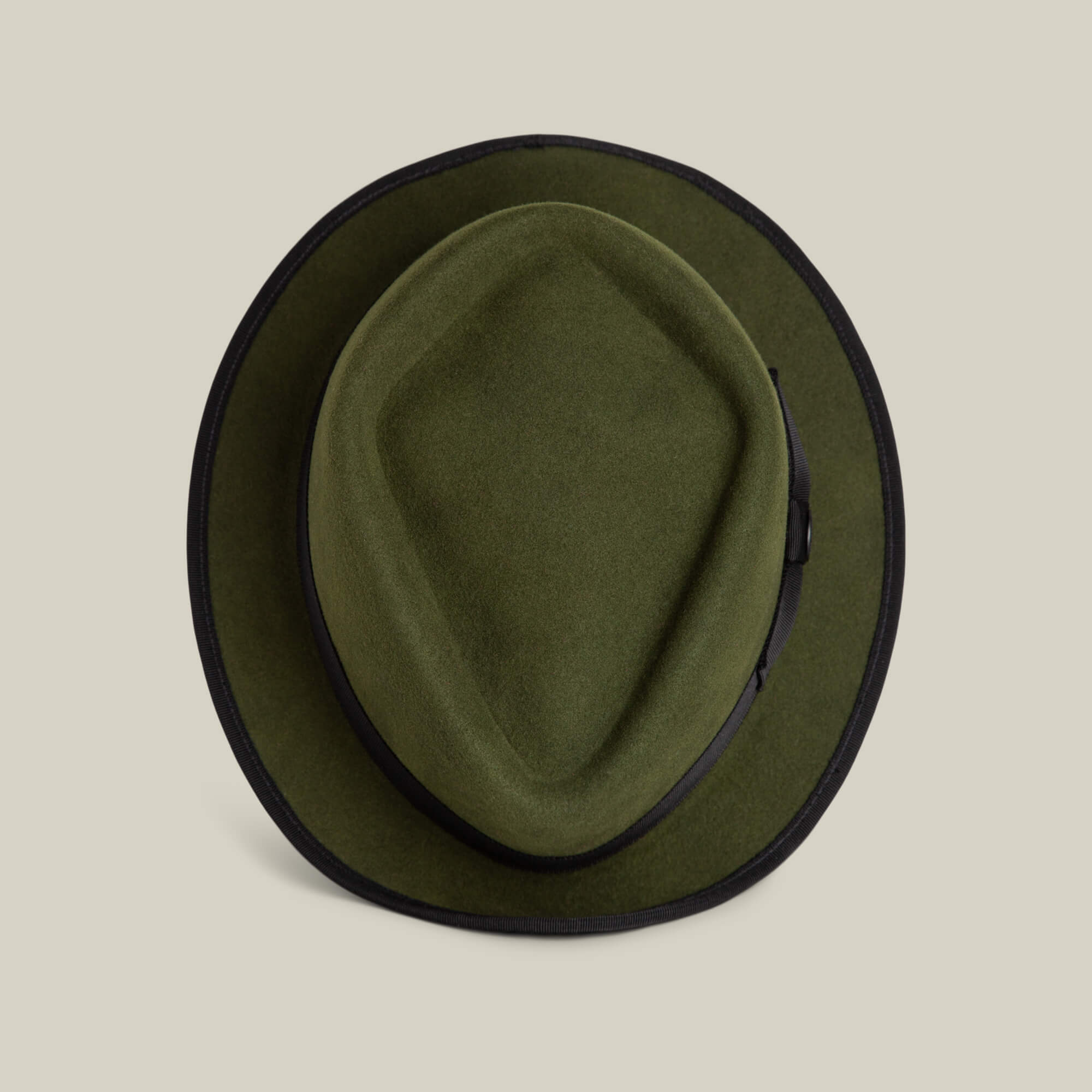The Goorin Bros. Slick Carter is a green wool felt hat with a black band and trim, short brim style, shown from above on a beige background for effortless style.