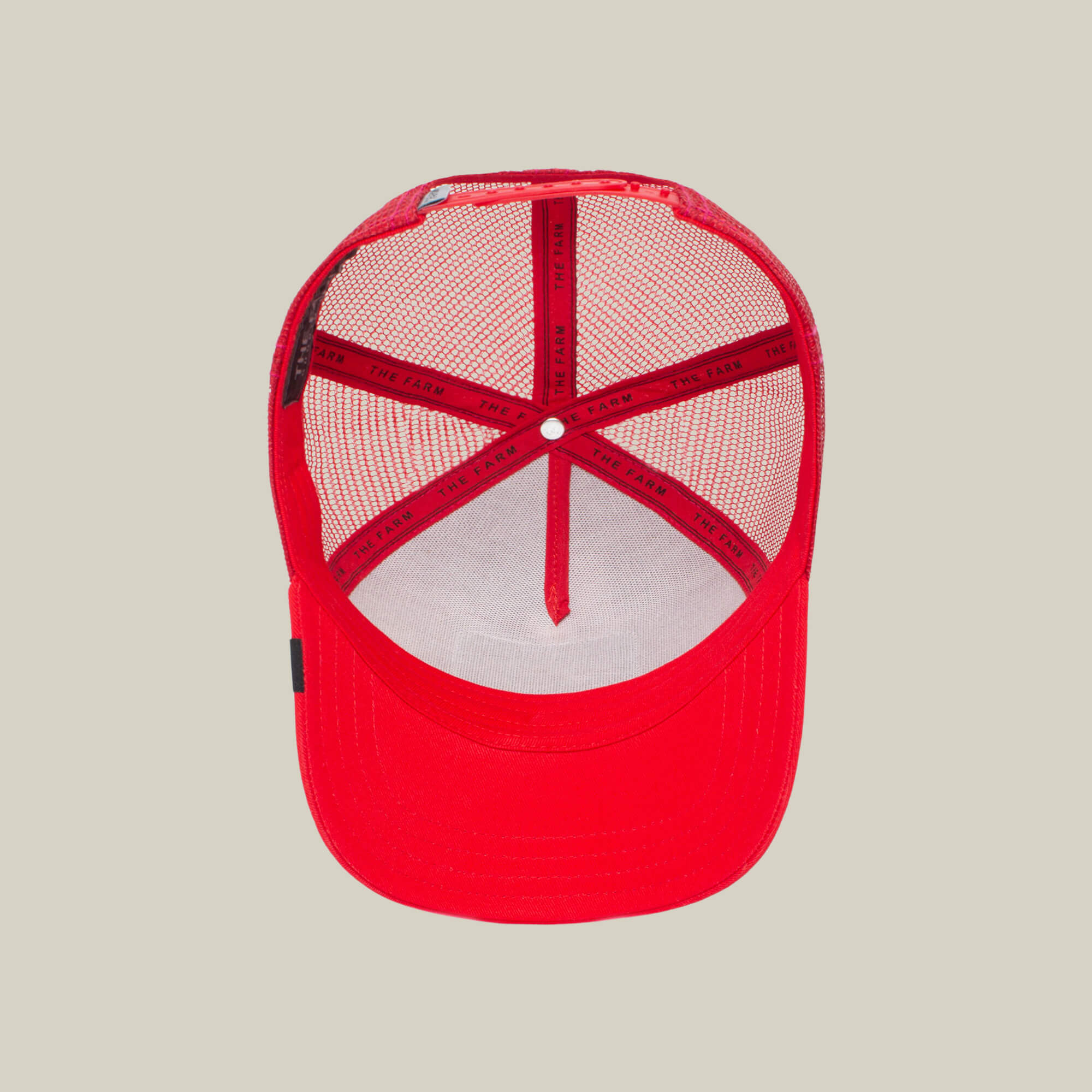 The Cock by The Farm is a red mesh trucker hat seen from above, revealing the inner mesh lining and bands. Its bold design draws inspiration from the rooster, a timeless emblem of resurrection and vitality.