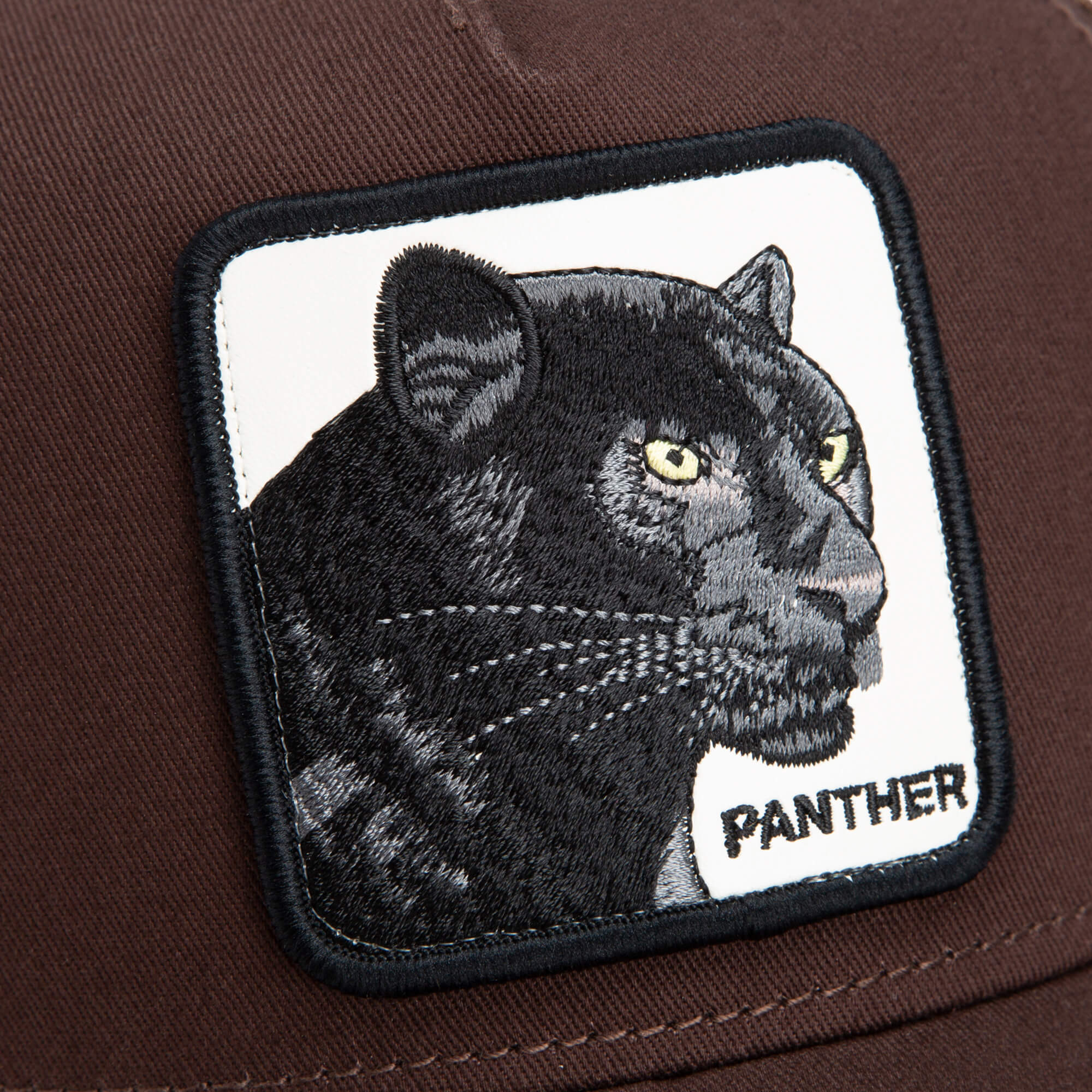 The Panther by Goorin Bros. is a brown trucker hat with a stitched patch showcasing a black panther’s face and the word "PANTHER" embroidered below.