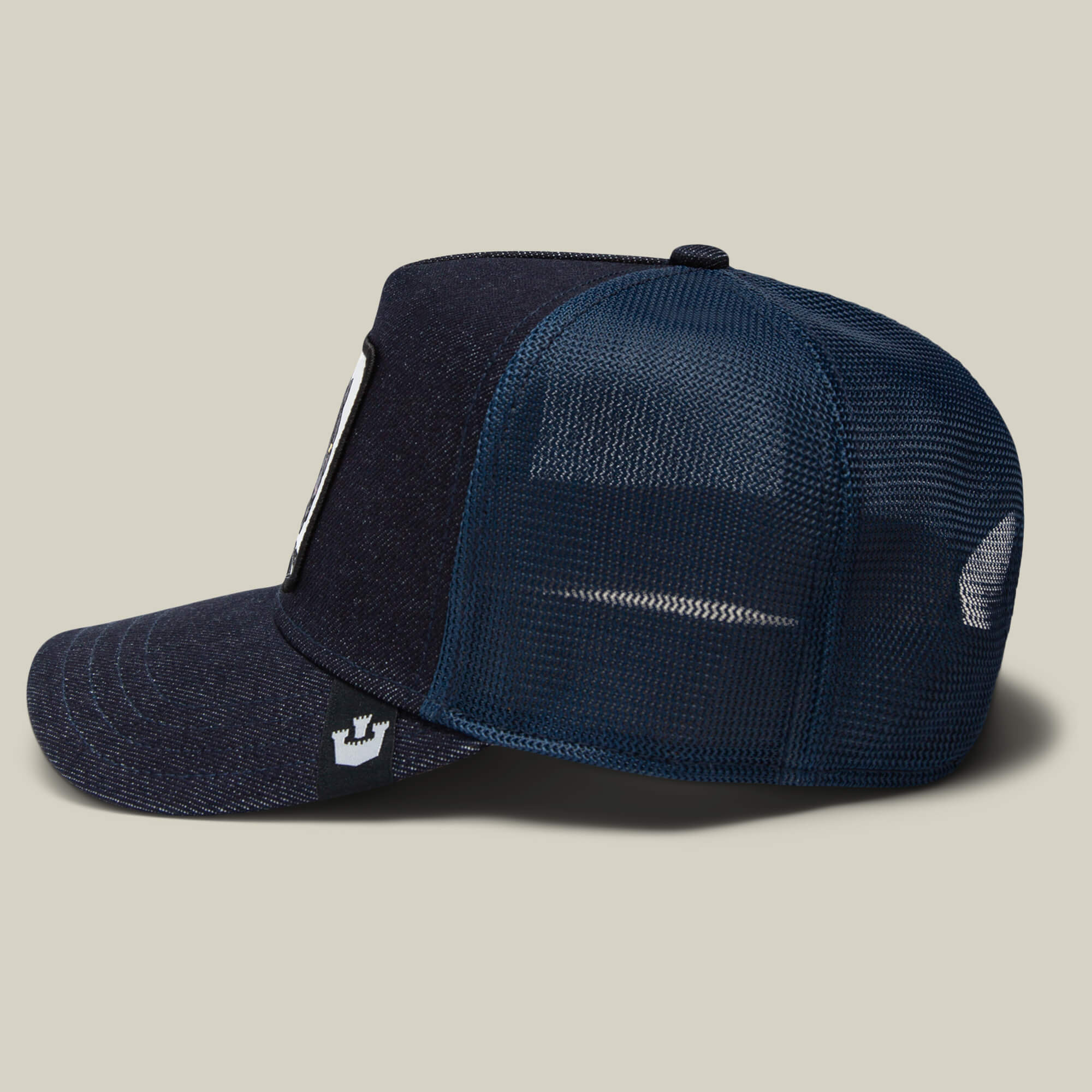 A side view of The Panther, a navy blue trucker baseball hat by Goorin Bros., featuring a mesh back and fabric front panel, shown against a plain light background.
