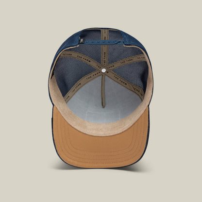 An inside view of The Panther trucker hat by Goorin Bros. reveals a tan brim, blue mesh panels, and an interior hatband branded with GOORIN BROS.